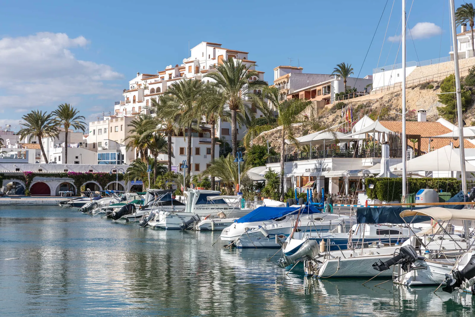 Embarcaciones amarradas en el puerto de Moraira frente al edificio del Club Náutico